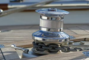 stainless steel winch on a teak wood deck.