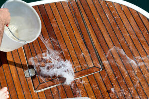 washing the deck with water throwed from a plastic buket.